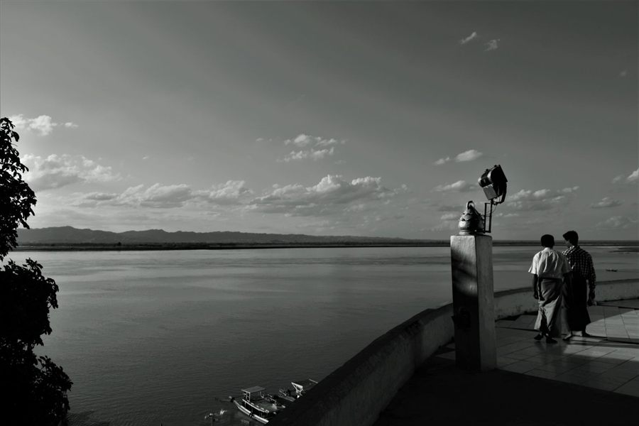 Black-and-white view of two people looking out over the Ayeyarwady River on an Irrawaddy cruise stop